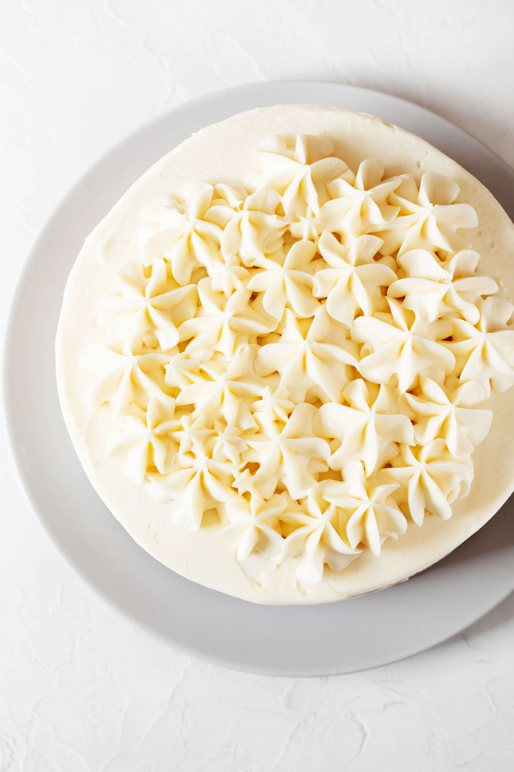 The top of a frosted, round white cake. It has been decorated with star shapes of buttercream frosting.