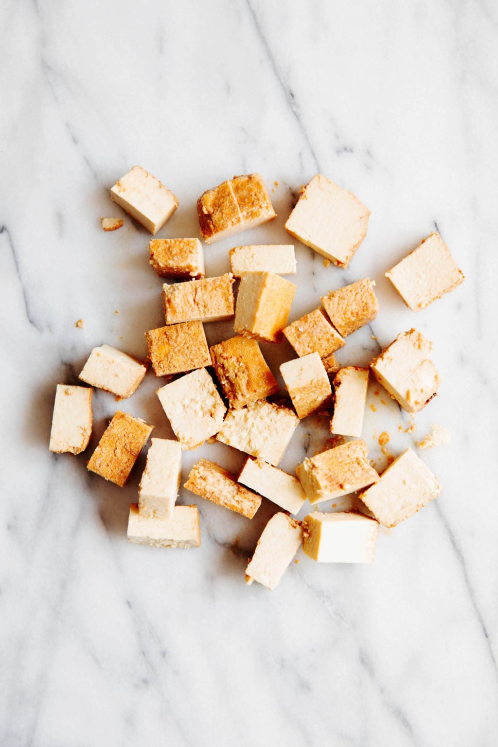 Cubed tofu rests on a white marble surface.