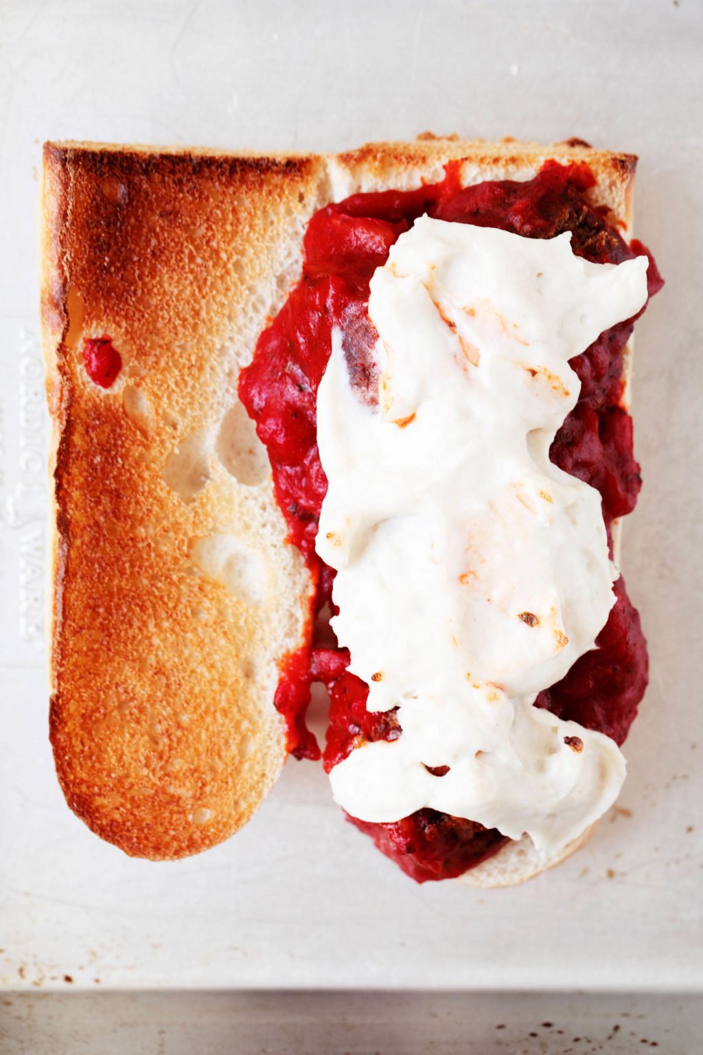 An overhead image of a half sandwich, which is made with plant-based meatballs and smothered in a white cashew cheese sauce.