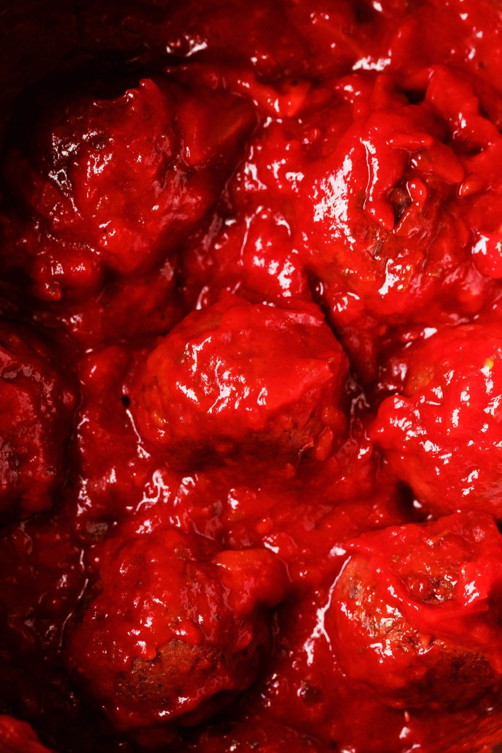 A batch of plant-based meatballs is simmering in bright red marinara sauce.