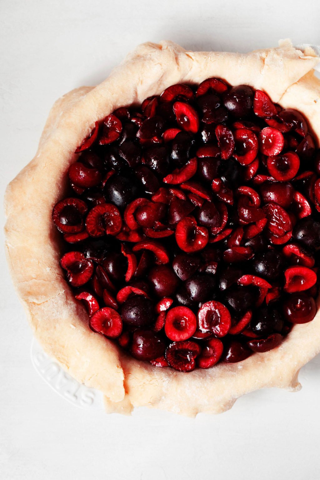 Dark, sweet cherries have been piled into a crust-lined pie baking dish. 