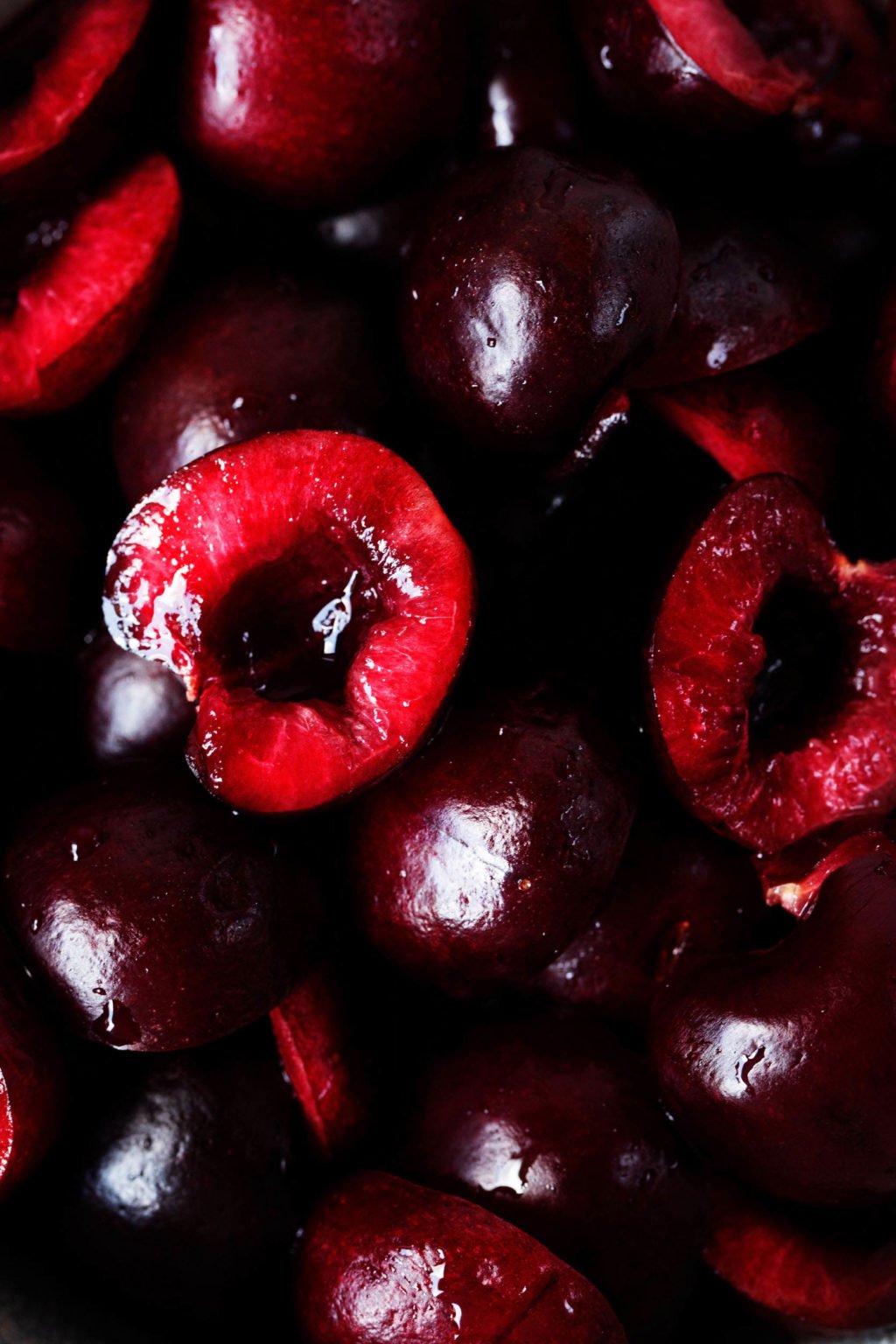 A zoomed in photograph of cut, dark red stone fruits.