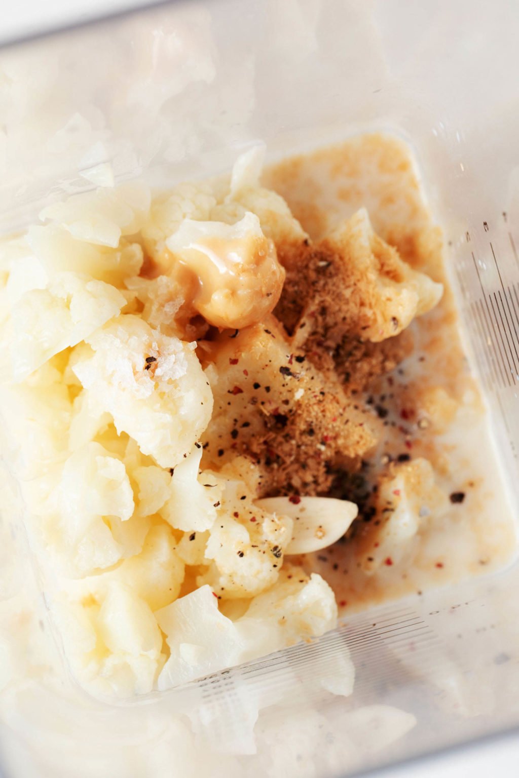 A creamy, vegan cauliflower Alfredo sauce is being prepared in a blender.