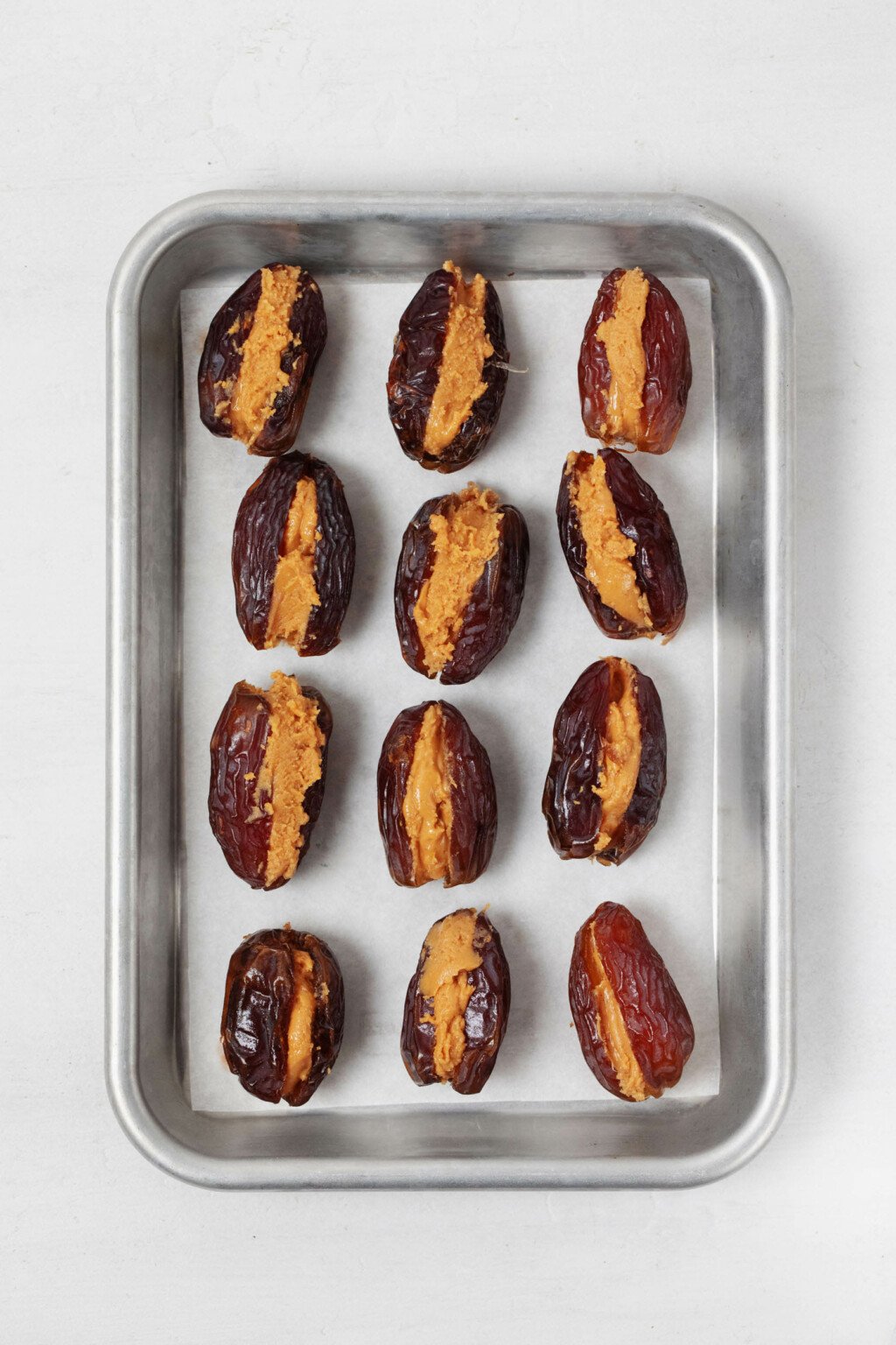 A small, metal tray is covered in Medjool dates stuffed with peanut butter.