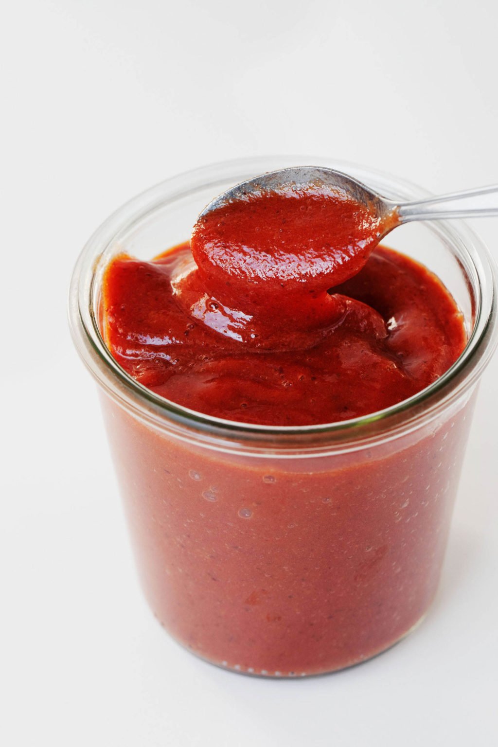 A mason jar holds red orange, date BBQ sauce.