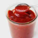 A mason jar holds red orange, date BBQ sauce.