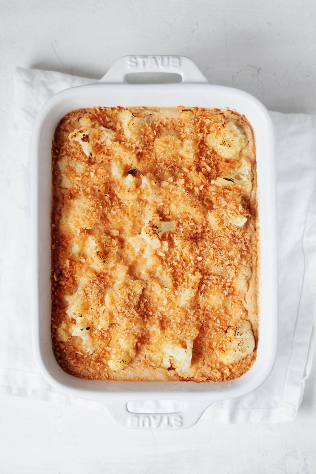 An overhead image of a rectangular baking dish. It has been filled with baked vegetables and a crispy bread crumb topping.