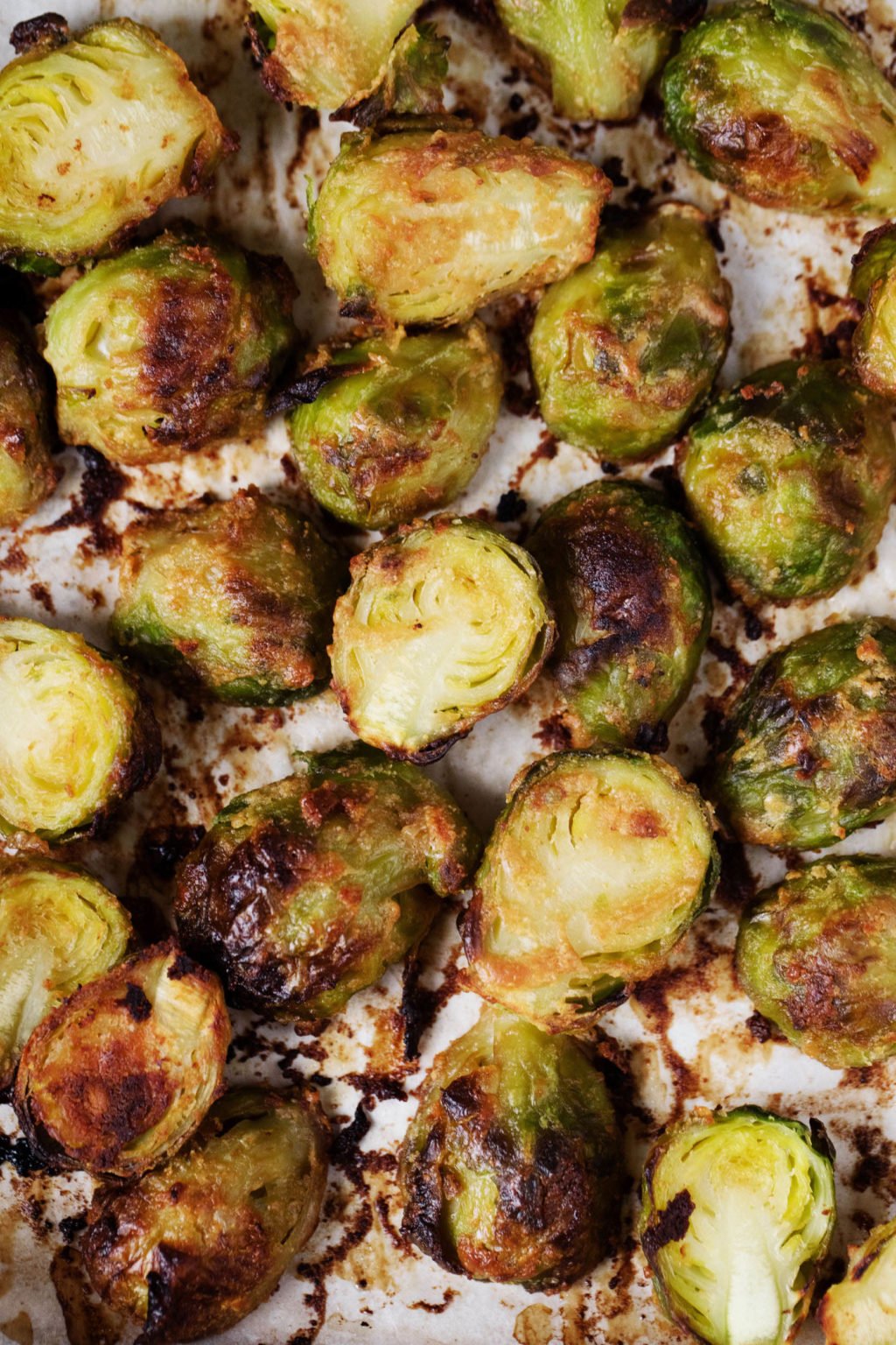 A lined baking sheet is topped with crispy, roasted autumn vegetables.