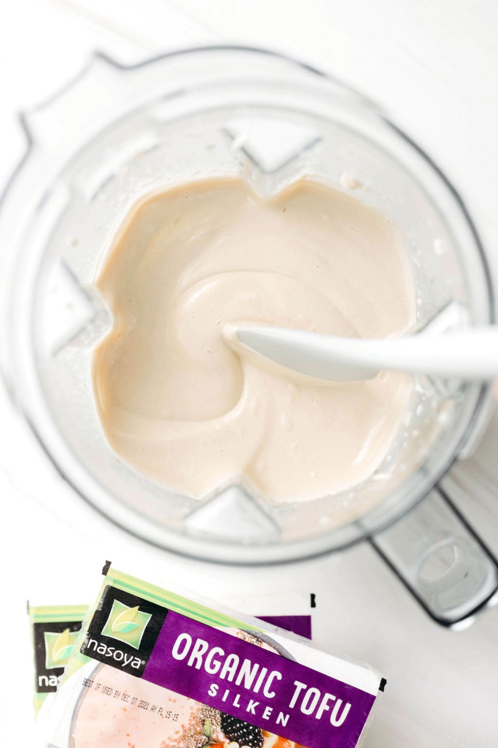 An overhead image of the container of a blender. It's filled with a creamy white mixture.