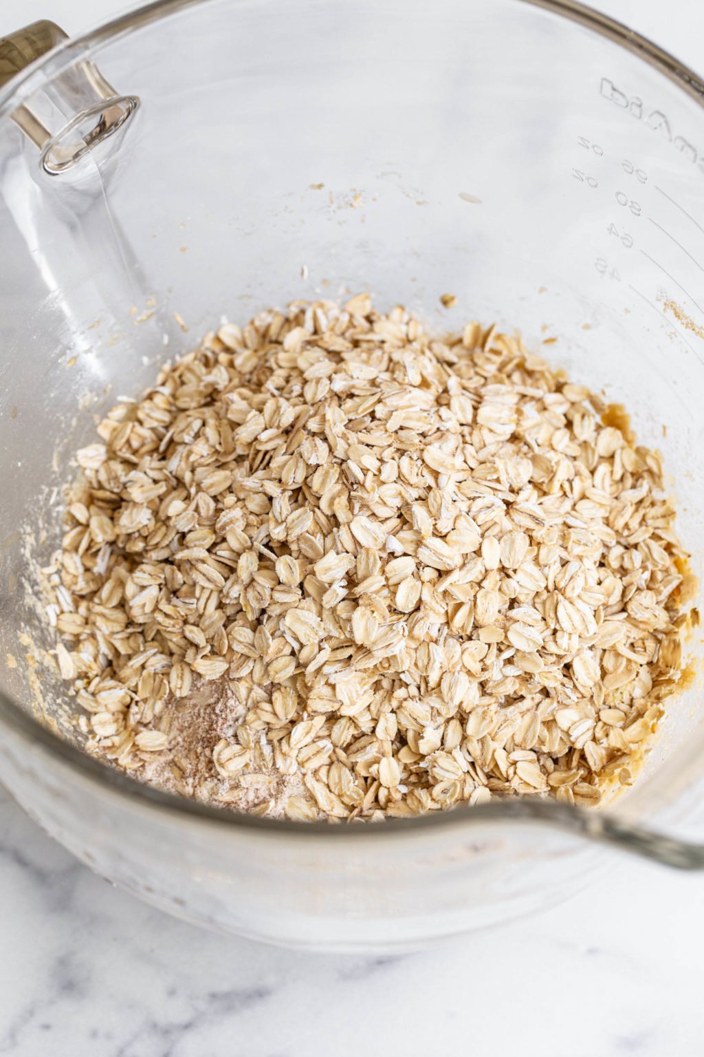 The bowl of a stand mixer is filled with rolled oats.