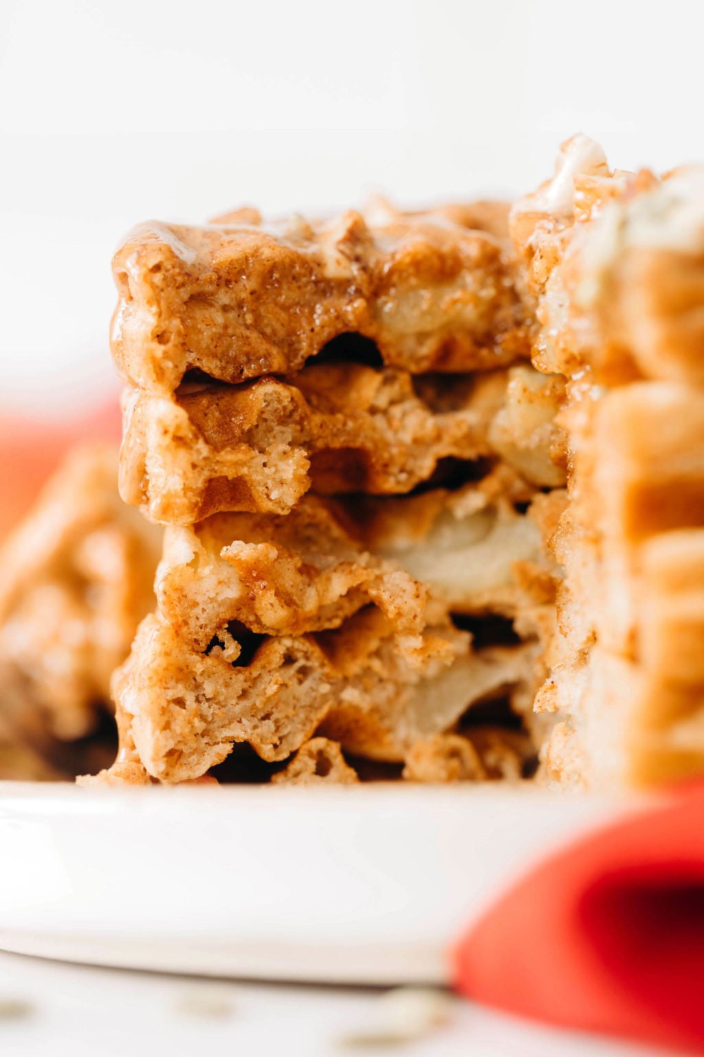 A thick, fluffy stack of vegan apple cinnamon waffles has been cut into, revealing layers of waffle and apple inside.