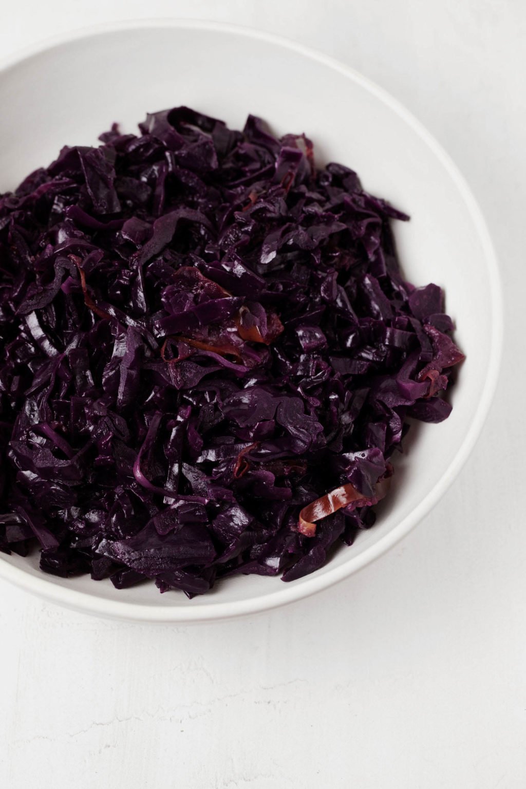 A white bowl holds braised red cabbage and apples.