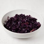 An angled photograph of braised red cabbage, resting on a white surface.