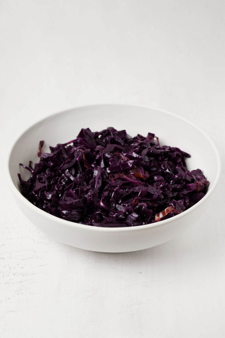 An angled photograph of braised red cabbage, resting on a white surface.