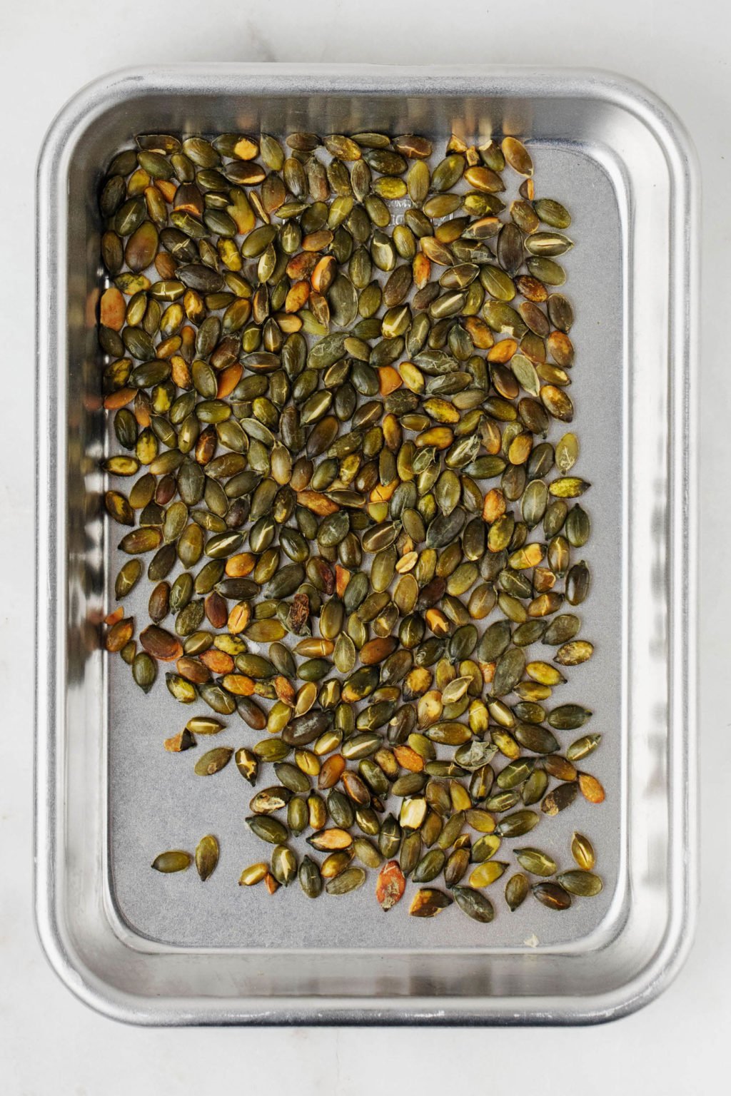 A rimmed baking sheet has been used to roast pepitas.