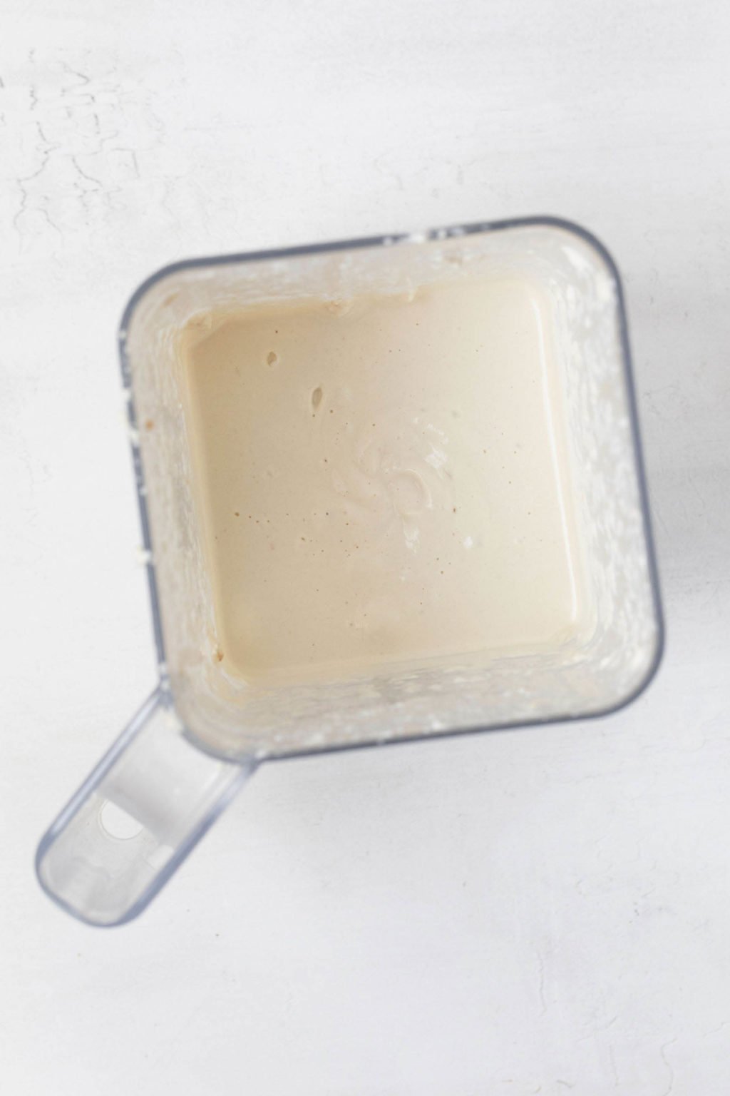 An overhead image of a blender, filled with a creamy white mixture.