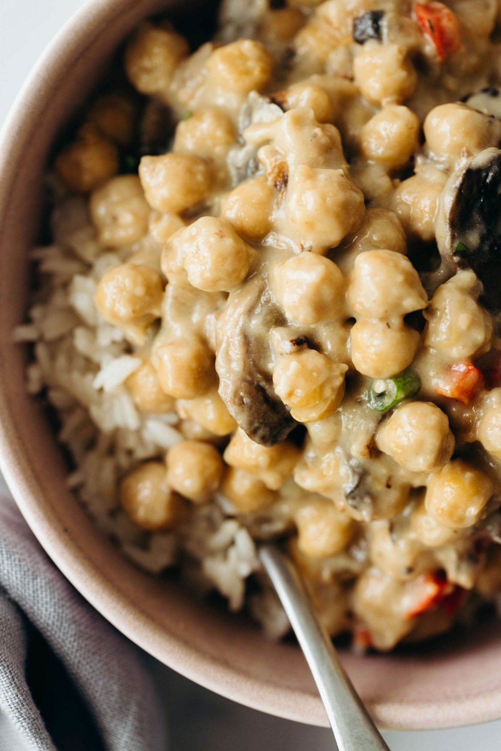 A dish of chickpeas à la King has been served over a bed of brown rice.