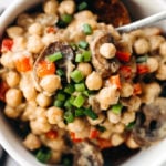 A close, overhead image of cooked beans, chopped scallions, and red peppers with mushrooms.