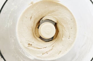 An overhead image of a food processor, which is filled with a creamy white mixture.