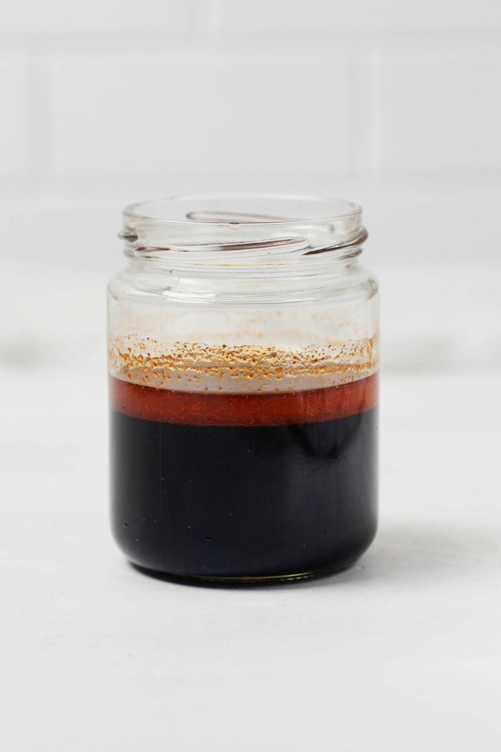 Un frasco de conservas de vidrio se llena con un adobo de color marrón oscuro.