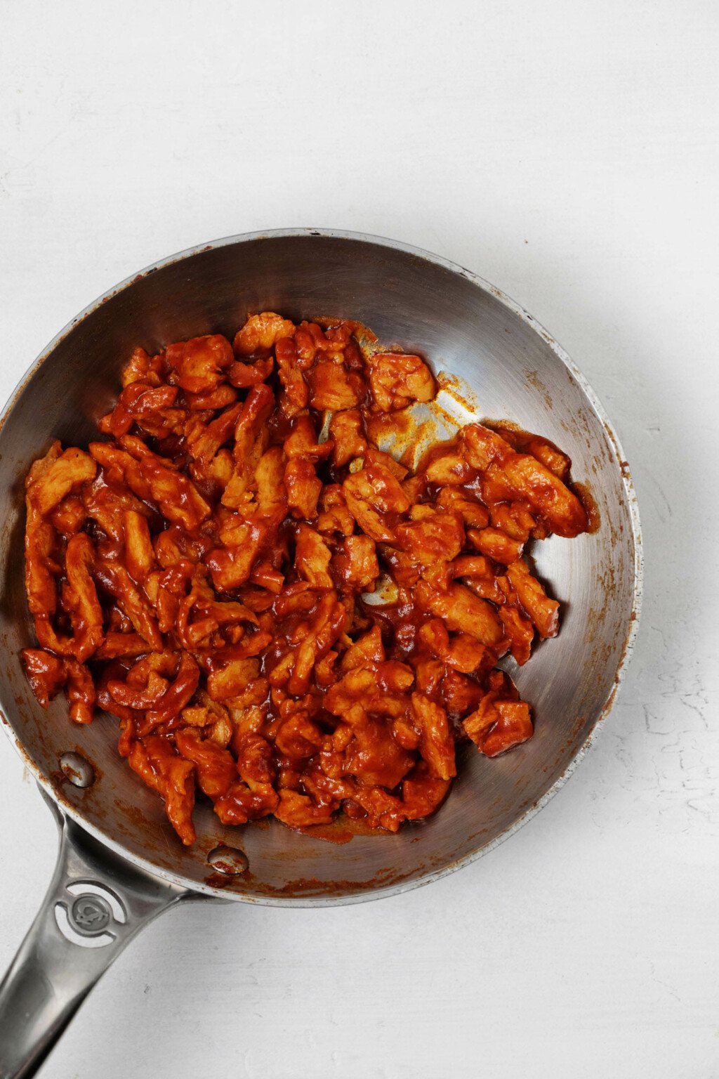 A frying pan has been filled with a vegan protein and a red, thick sauce.