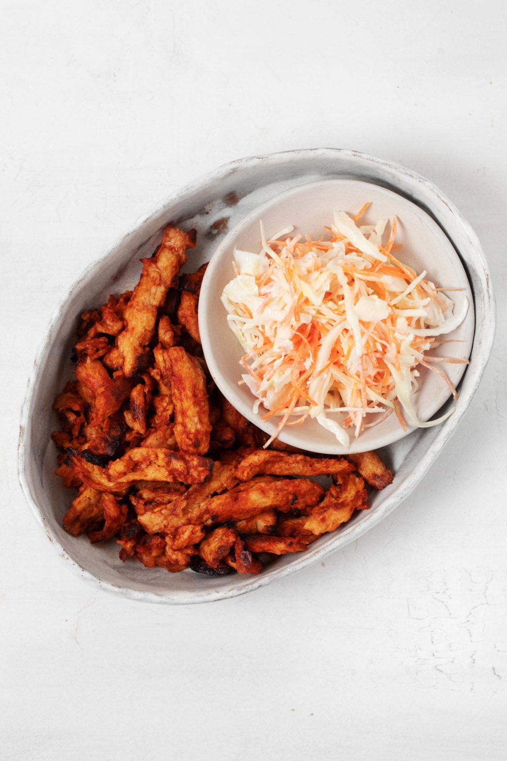 A vegan protein is being served on a small, oval platter with coleslaw.