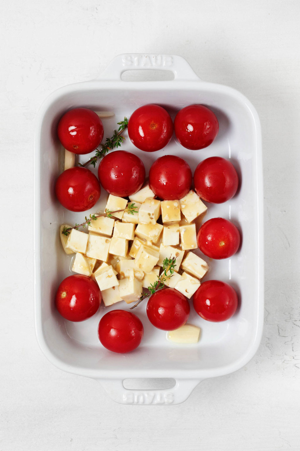 A rectangular baker holds grape tomatoes and cubed tofu.