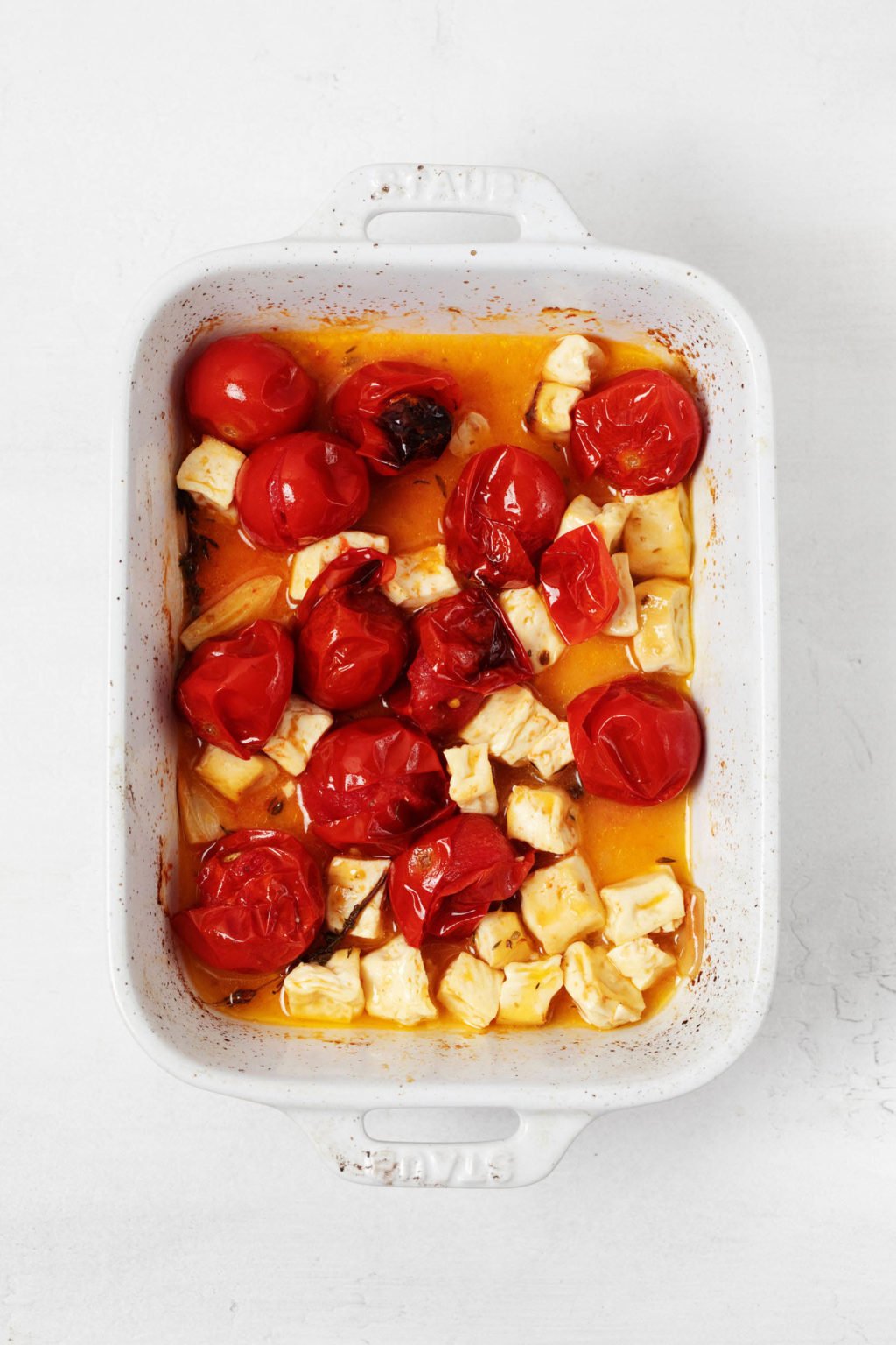 Tomatoes and tofu have been baked in a rectangular, white dish.
