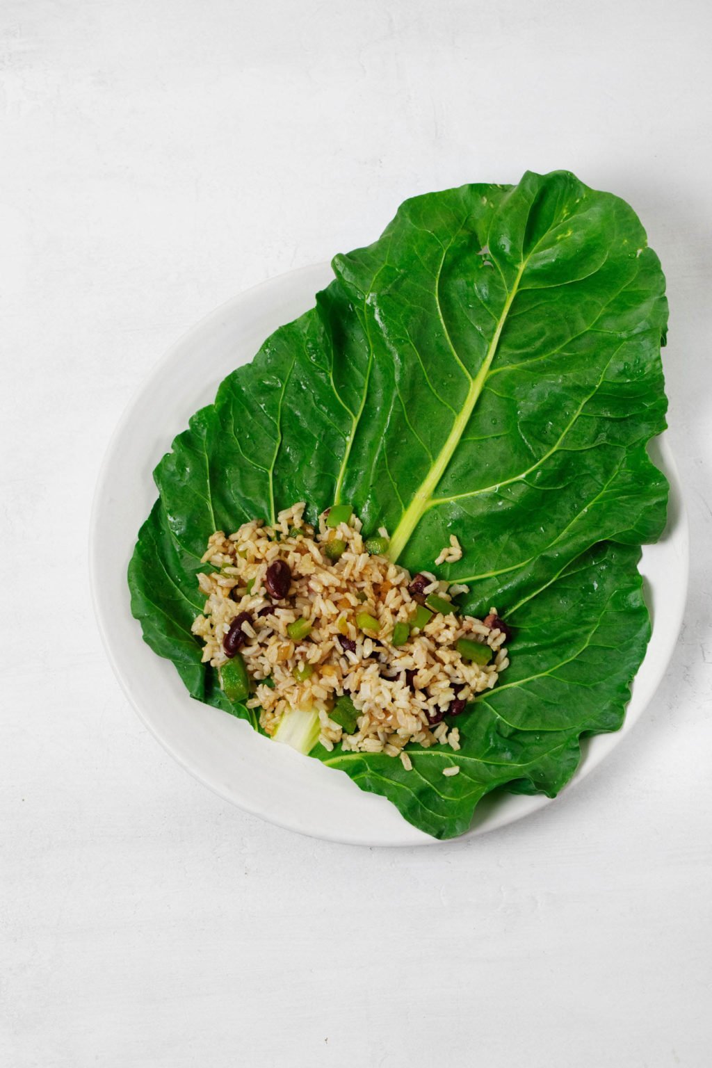 A large, steamed collard green leaf has been filled with rice, beans, and vegetables.