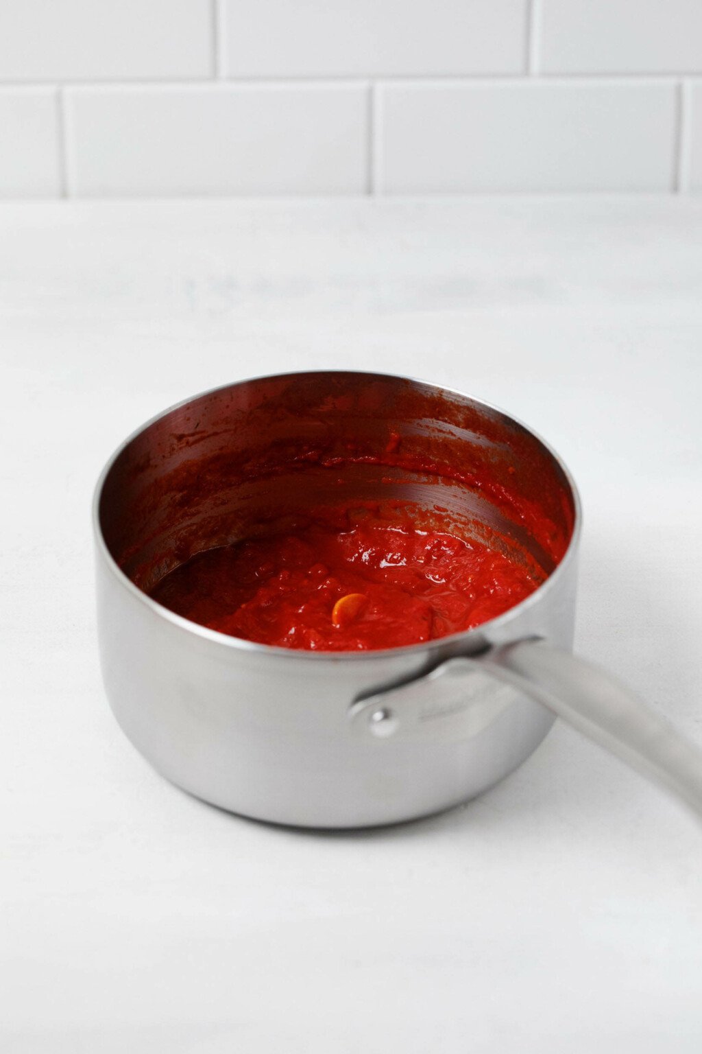 A stainless steel pot is being used to simmer a 20 minute, homemade marinara sauce.
