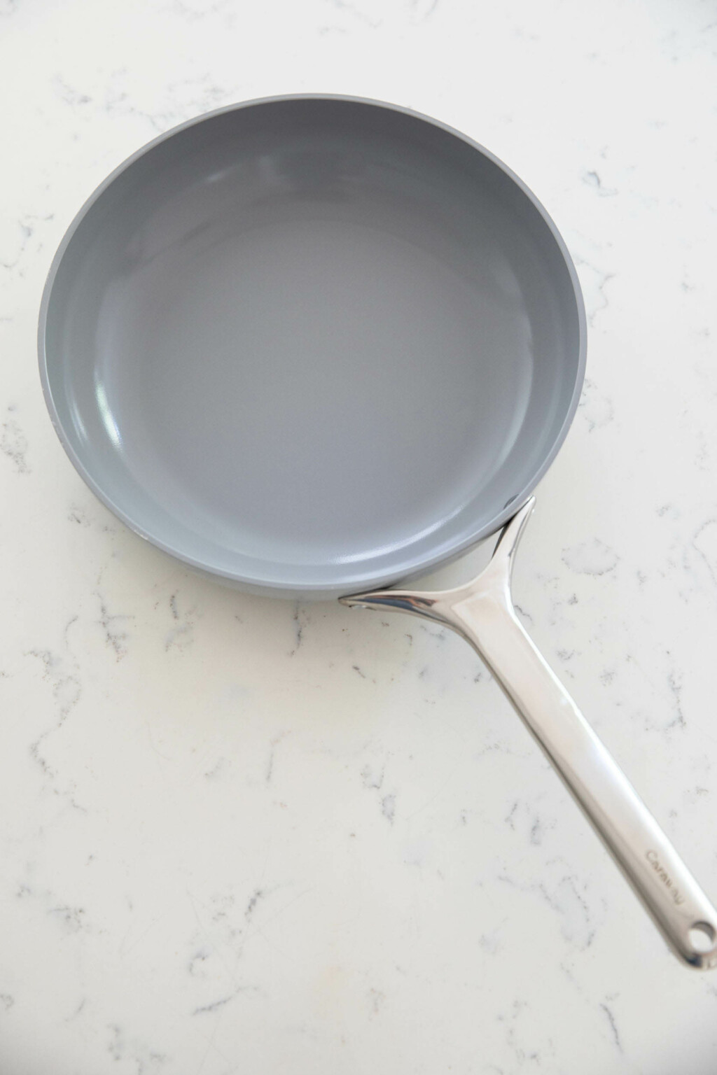 A gray frying pan rests on a white, marbled surface.