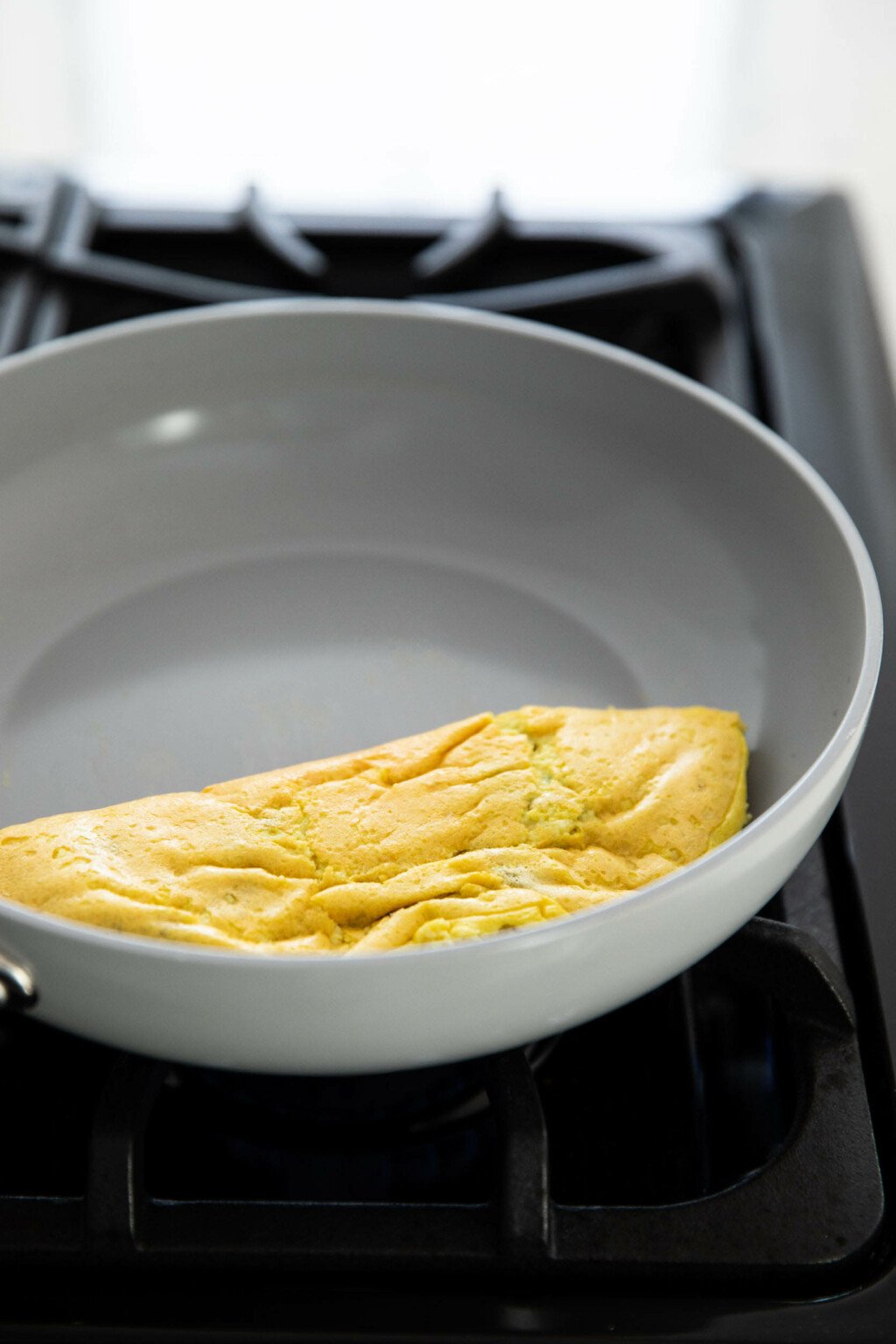 A gray, nonstick frying pan is being used to cook an omelet.