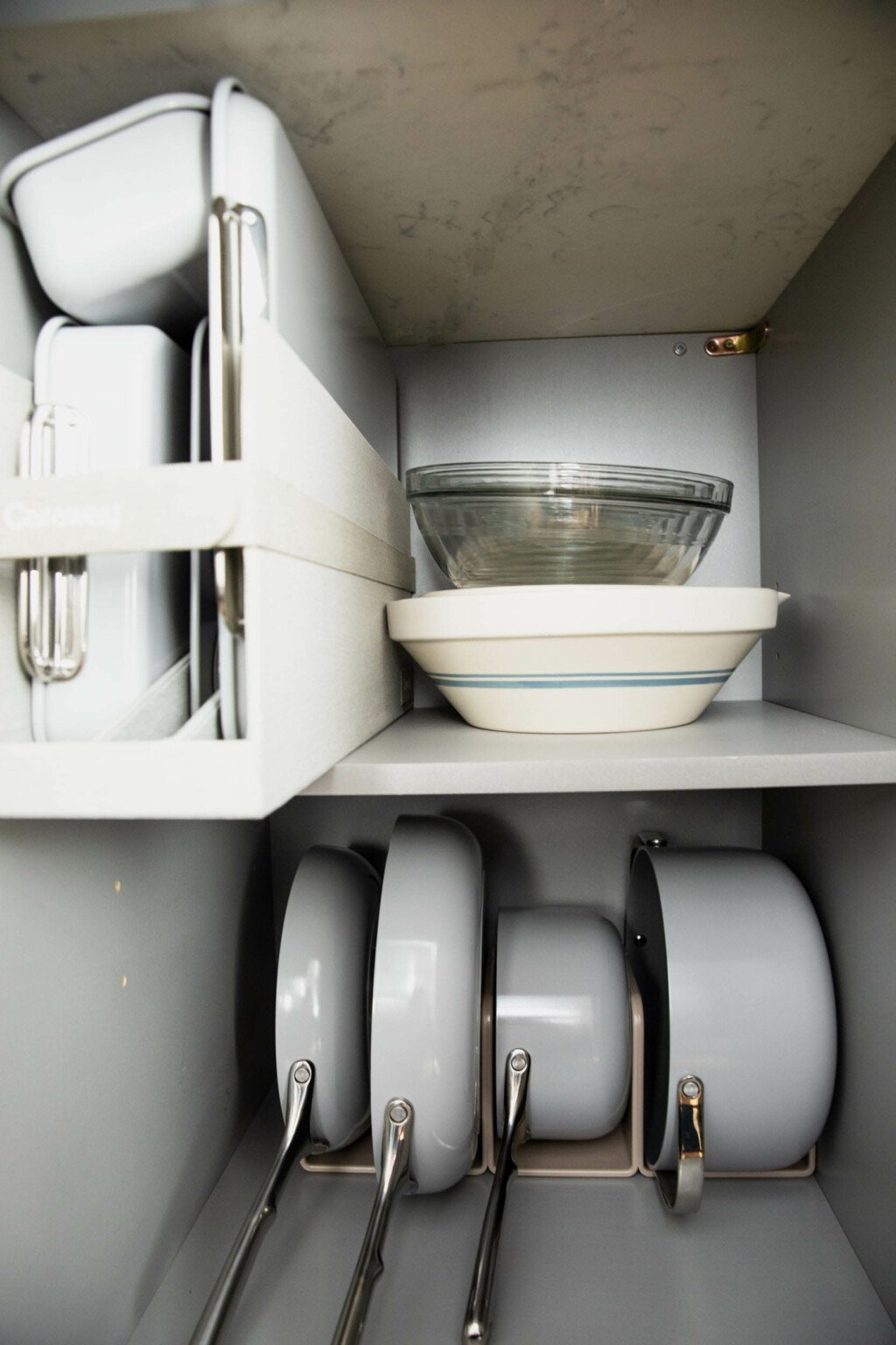 A gray storage drawer in a small, urban space is filled with storage for the Caraway Cookware set and baking set.