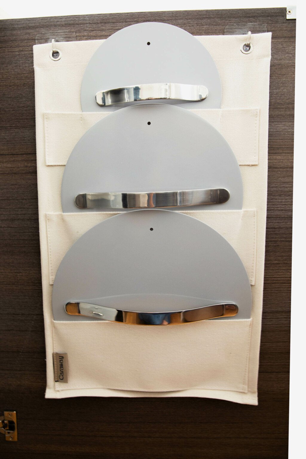 Lids for the Caraway Home cookware set are stored on the back of a pantry door.