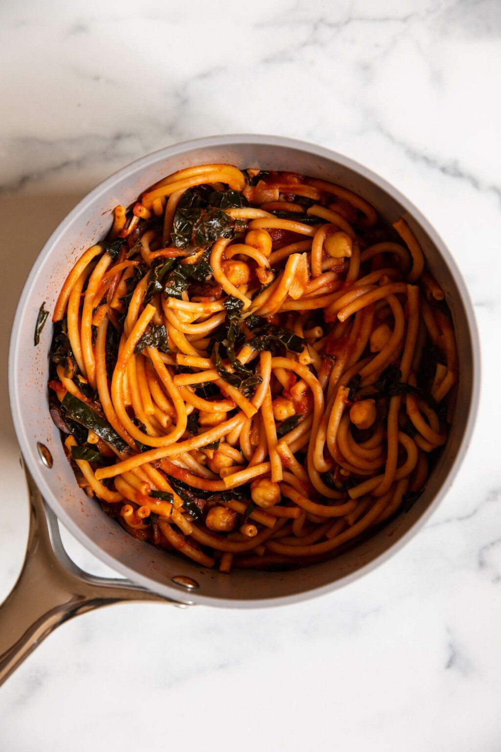 A gray colored sauce pot holds freshly made pasta.