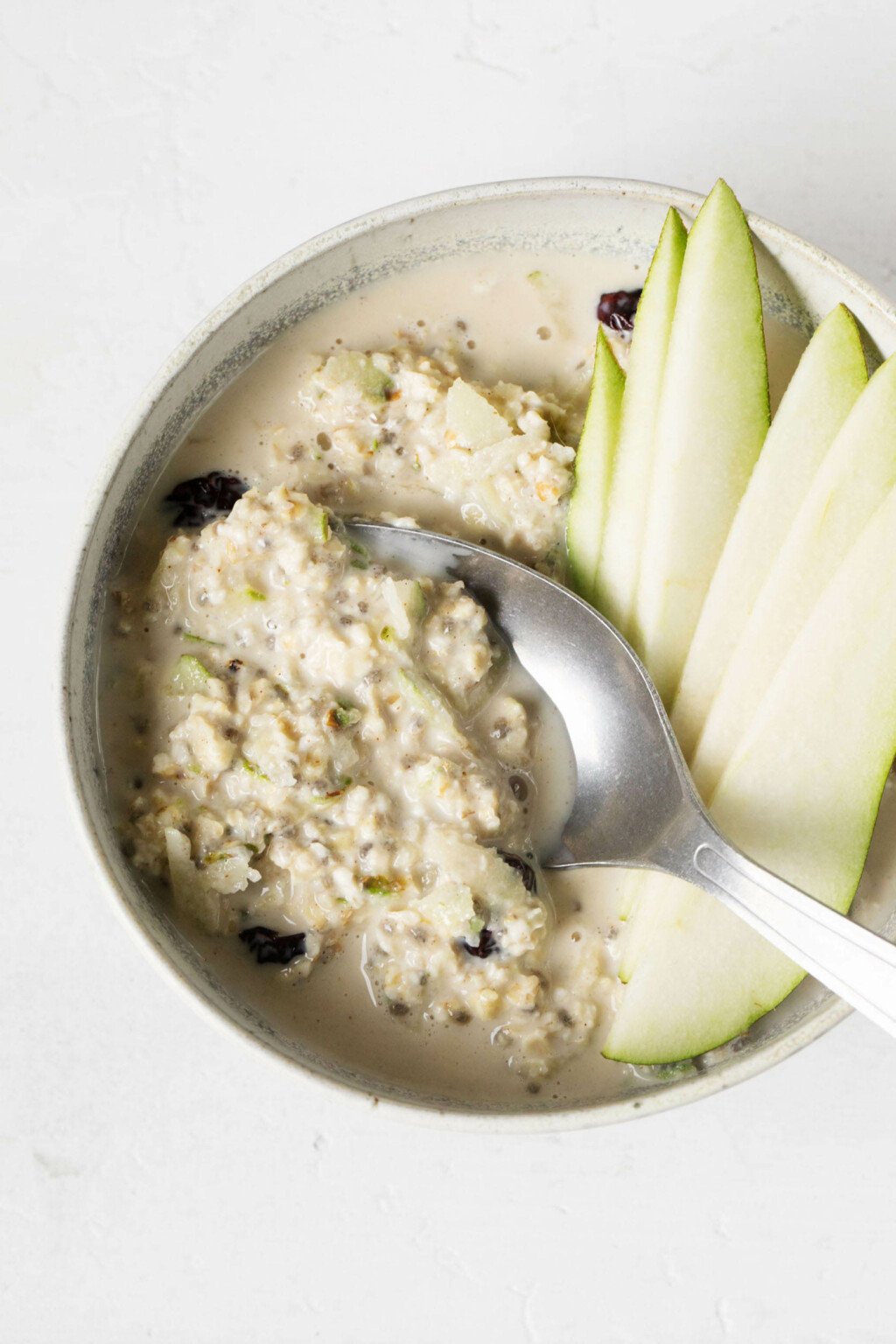 A bowl of ginger pear muesli is garnished with thin pear slices.