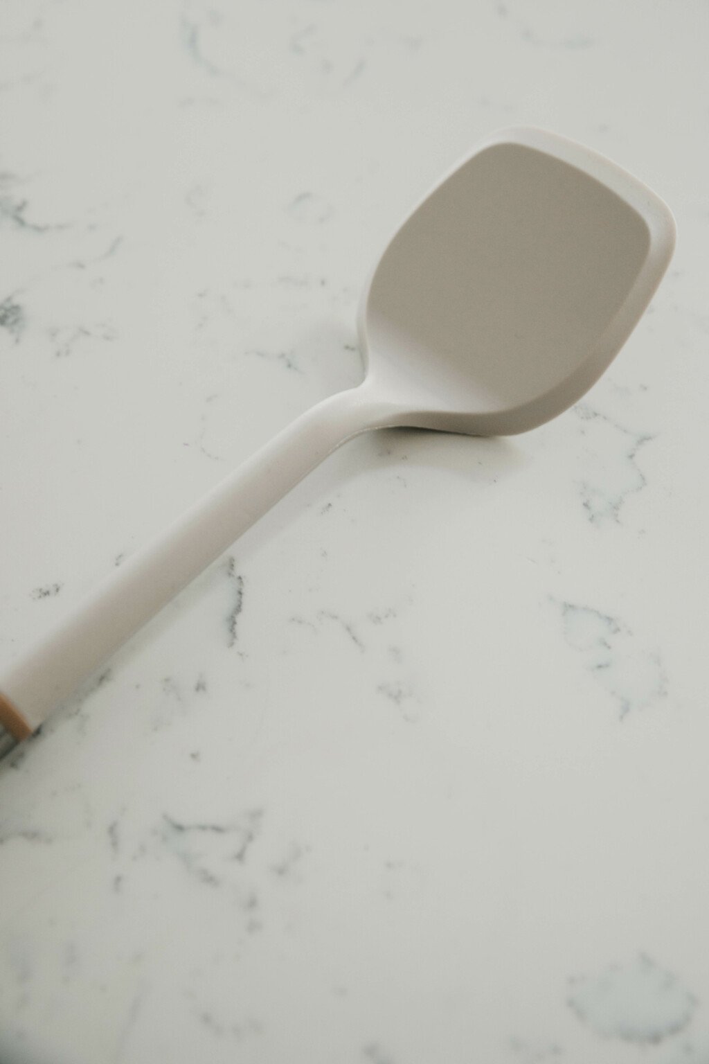 A silicone spatula rests on a white marble surface.