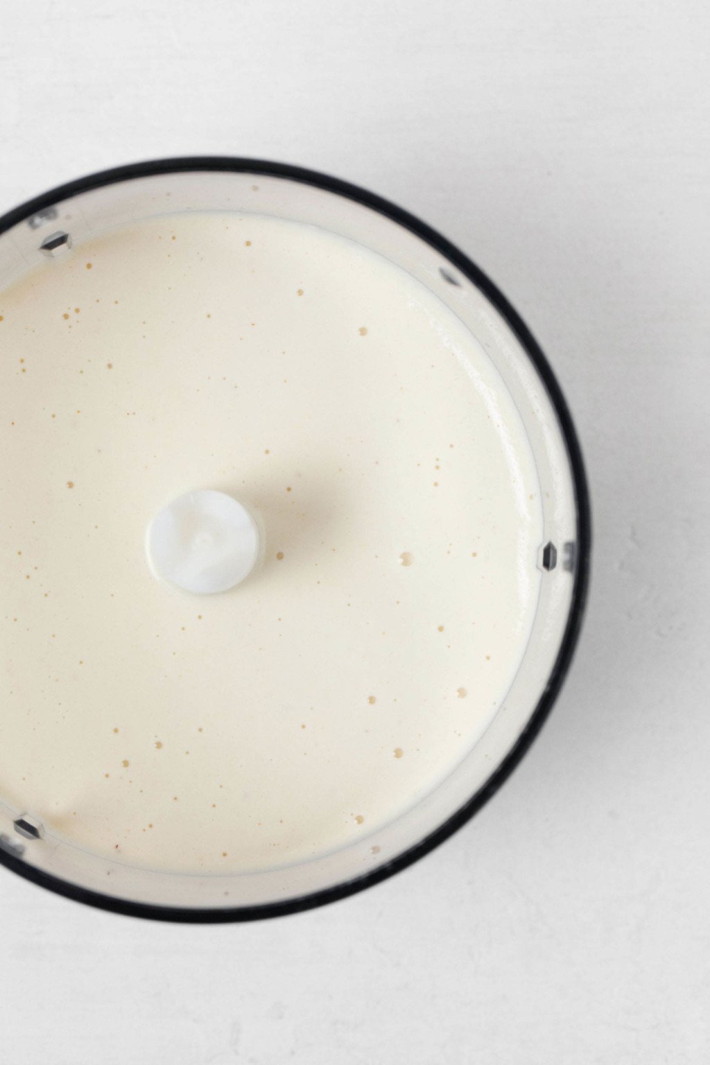 The bowl of a food processor has been filled with mayonnaise.