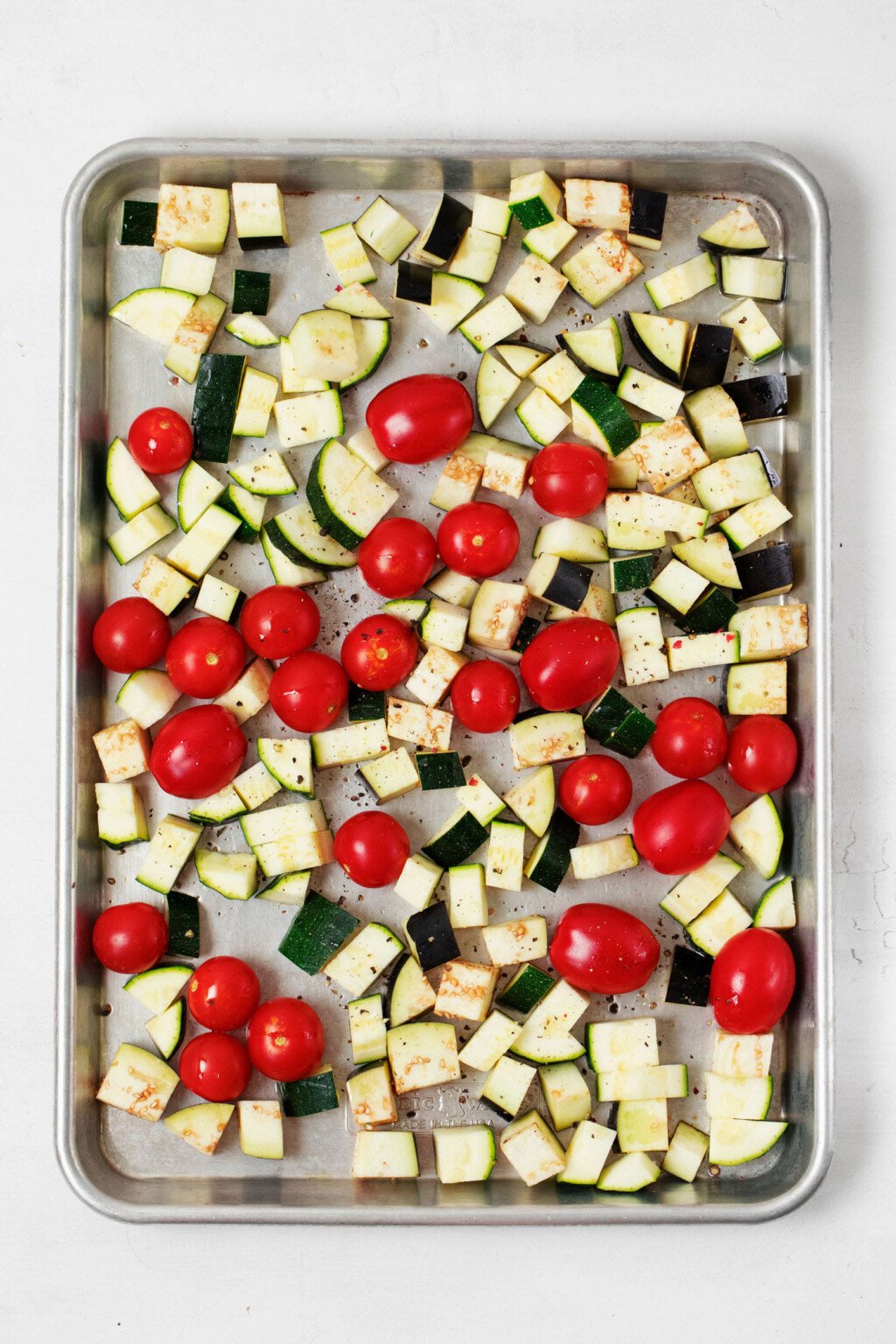 A roasting tray has been layered with summer vegetables.