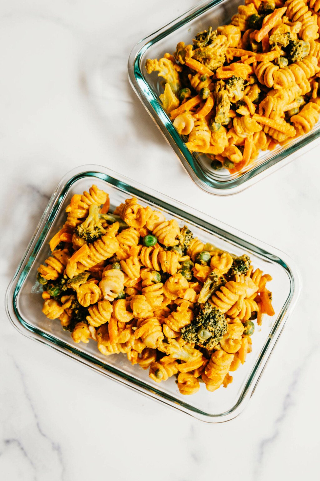 Two matching storage containers are filled with pasta salad—one of many easy vegan meal prep lunch ideas.
