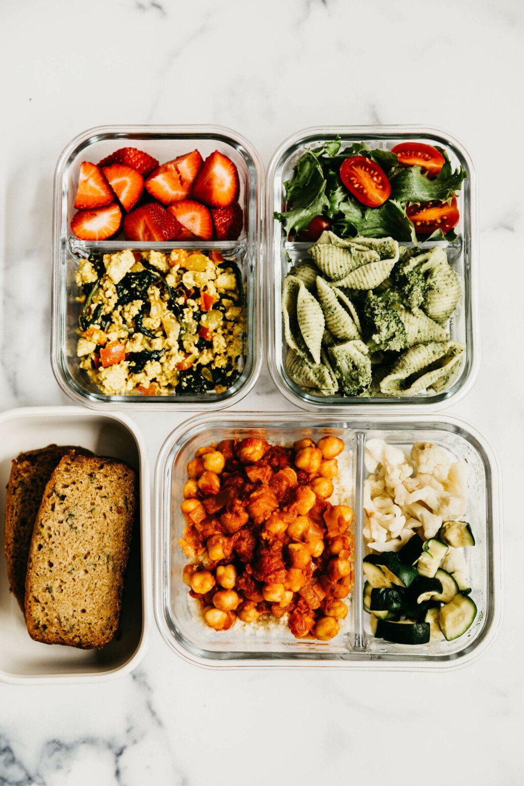 An overhead image of components of vegan meal prep, which have been packed in divided containers.