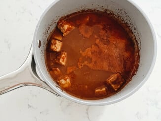 Cubes of tempeh have been simmered in a deep brown colored marinade.