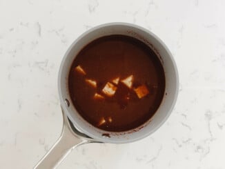 Cubes of tempeh and a marinade are in a small, gray saucepan.