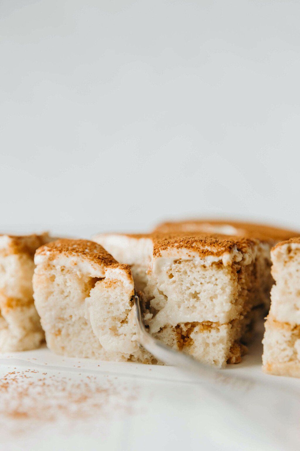 An angled photograph of vegan tiramisu, which is being cut into with a fork. 