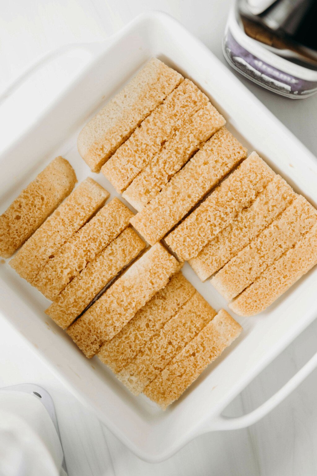 A white, square dish is used to hold rectangular pieces of cake.