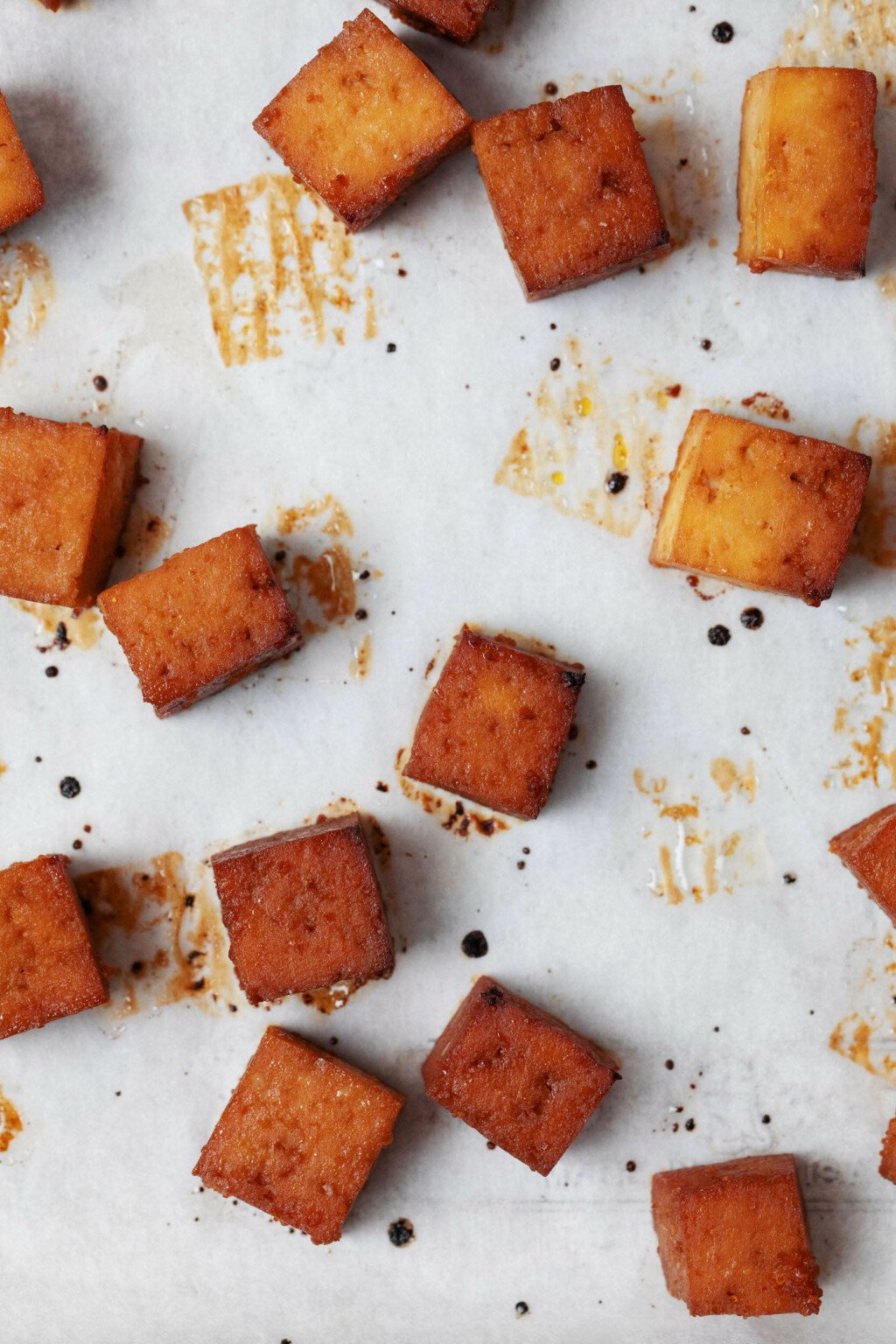 Teriyaki seasoned tofu cubes have just been baked and are emerging from the oven with crispy edges.