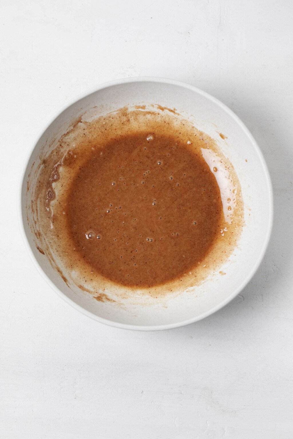 A small white bowl is filled with a brown, viscous liquid.