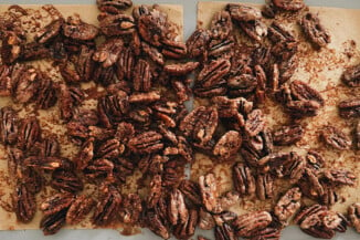 Crispy, baked pecan halves are resting on a baking sheet, fresh out of the oven.