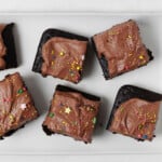 Frosted squares of a snack cake are laid out on a white platter. Each square is topped with decorative sprinkles.