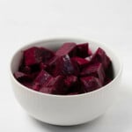 A small, round white bowl has been filled with marinated beets.